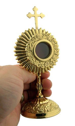 6 3/4" gold plated round reliquary with ornate floral design and cross on top held in hand against white background
