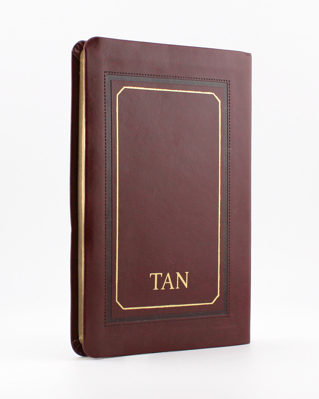 Brown leather-bound book titled TAN with gold embossed border and text on plain white background