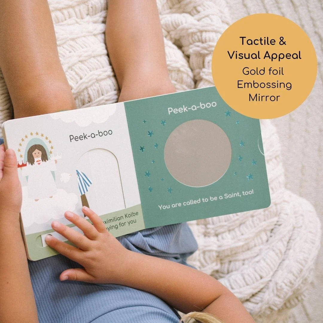 Child holding Peek-a-boo Saints 2 Catholic interactive board book with gold foil and mirror detail