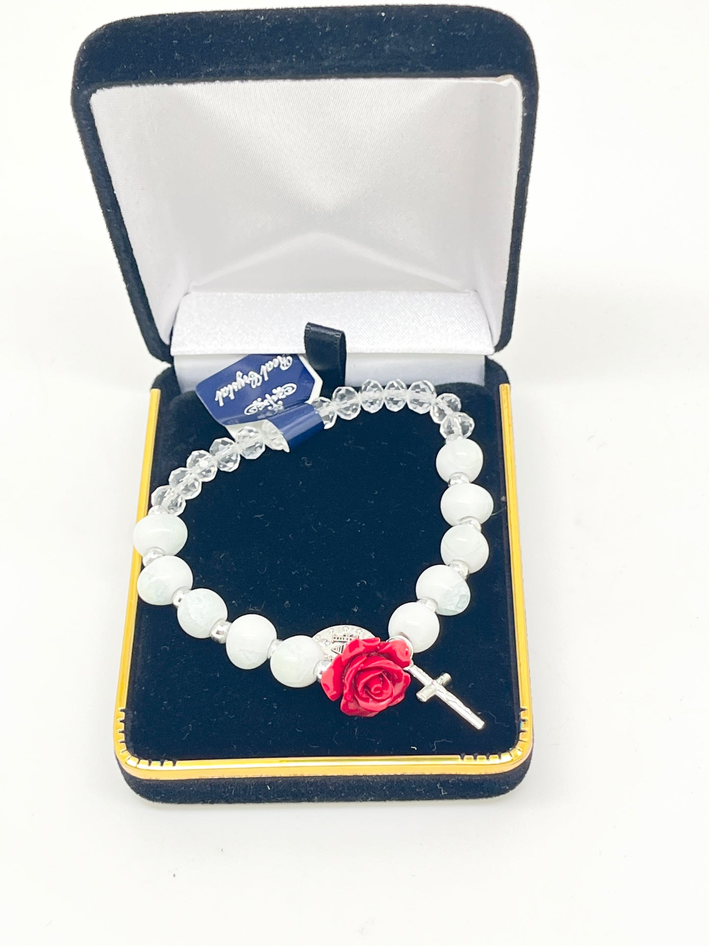 Stretch rosary bracelet with clear and white beads, red rose Our Father bead, silver Miraculous Medal, and cross charm in gift box.