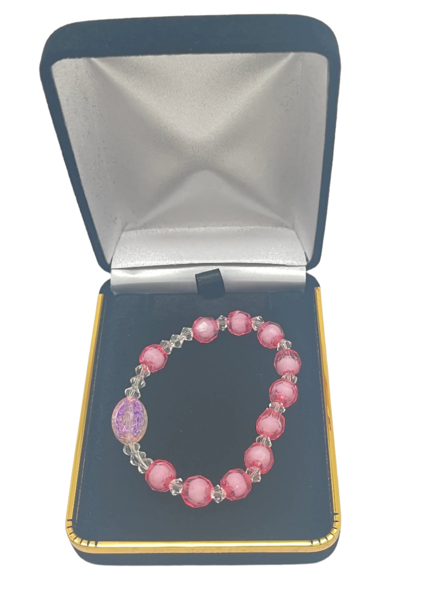 Pink acrylic children’s rosary bracelet with faceted beads and Miraculous, displayed in a black velvet jewelry box.