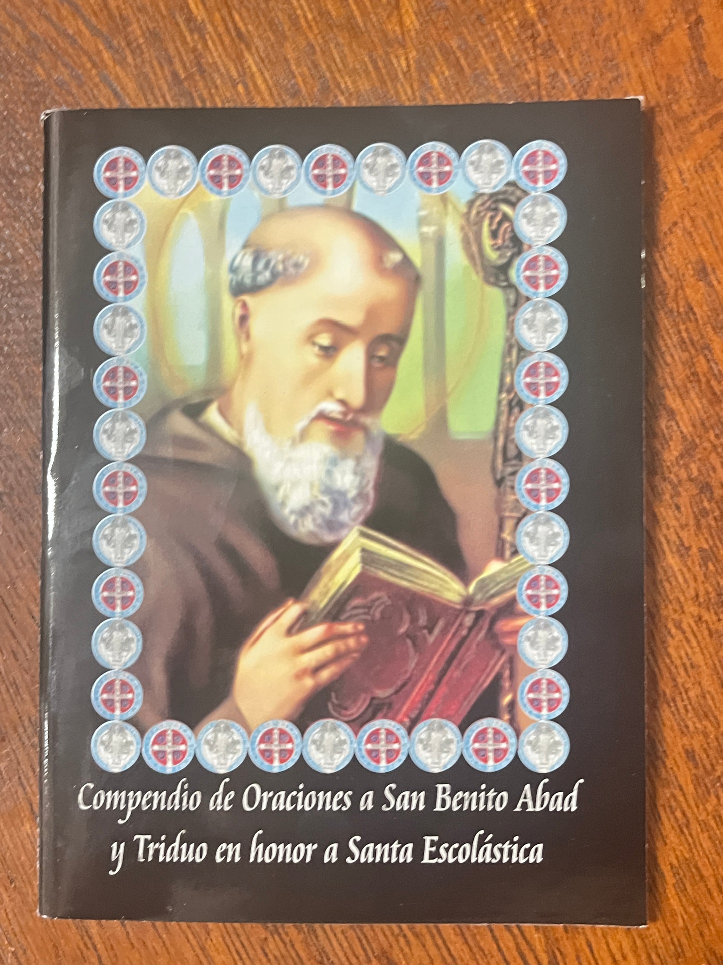 Prayer book featuring Saint Benedict and triduum prayers honoring Saint Scholastica with decorative saint medal border