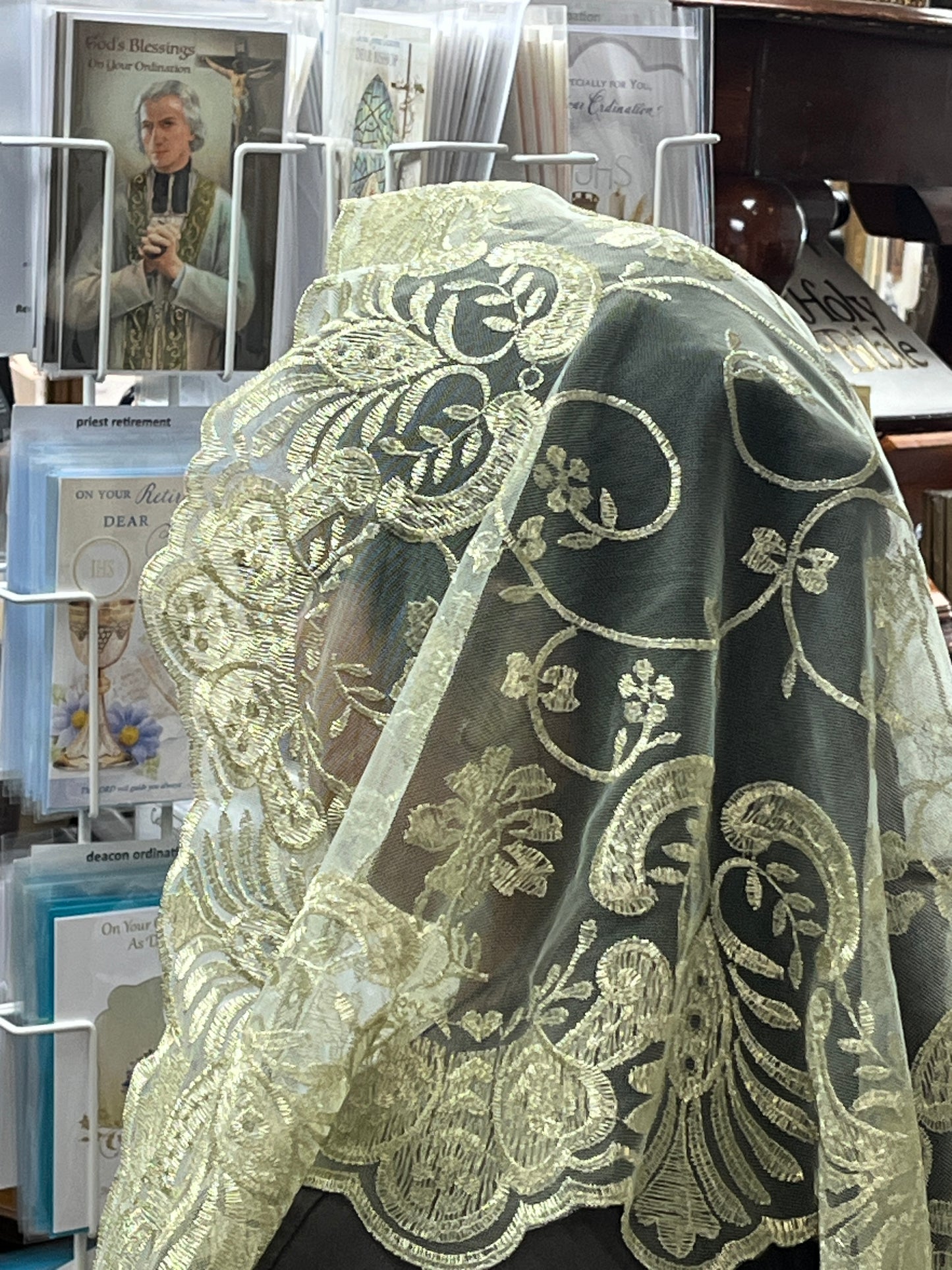 Ivory and metallic gold Spanish lace mantilla chapel veil with delicate floral motifs and scalloped edges, 51 inches long.