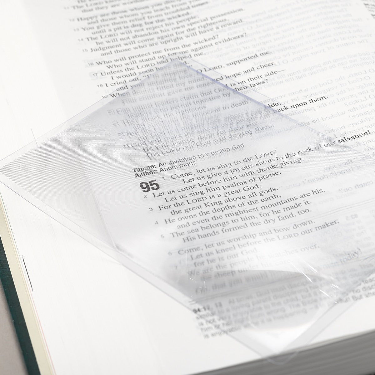 Clear pocket square magnifying sheet with 150% magnification, placed on book page showing text details