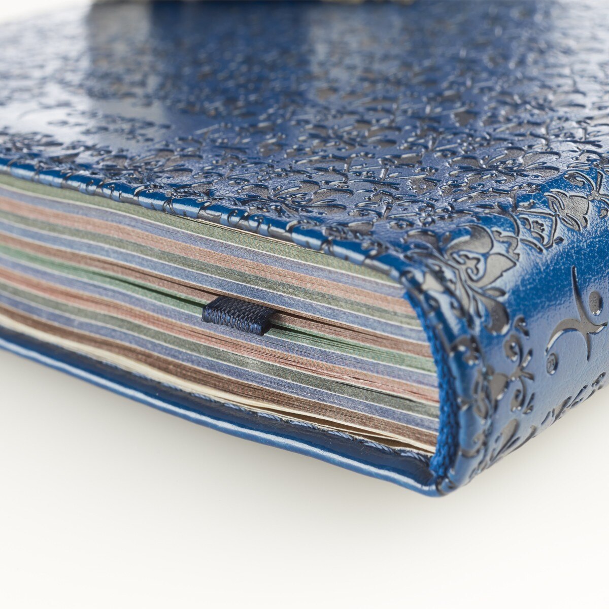 Close-up of navy blue faux leather devotional book cover with embossed floral design and colorful page edges