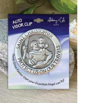 Round auto visor clip with Saint Christopher holding child, inscribed with "Protect us on our travels" and religious details
