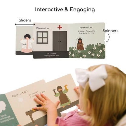 Peek-a-boo saints 2 Catholic board book open to interactive slider and spinner pages with child reading
