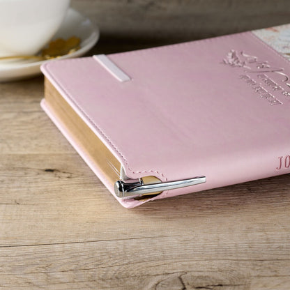Pink floral classic journal with elastic closure and silver pen holder on stitched cover edge.
