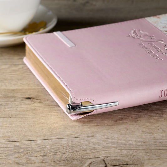 Pink floral classic journal with elastic closure and silver pen holder on stitched cover edge.