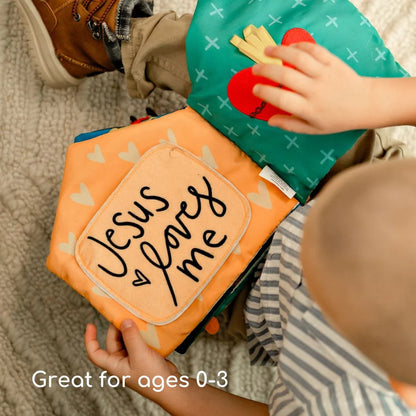Baby interacting with Catholic Mass Quiet Book featuring "Jesus loves me" page and felt communion wafers