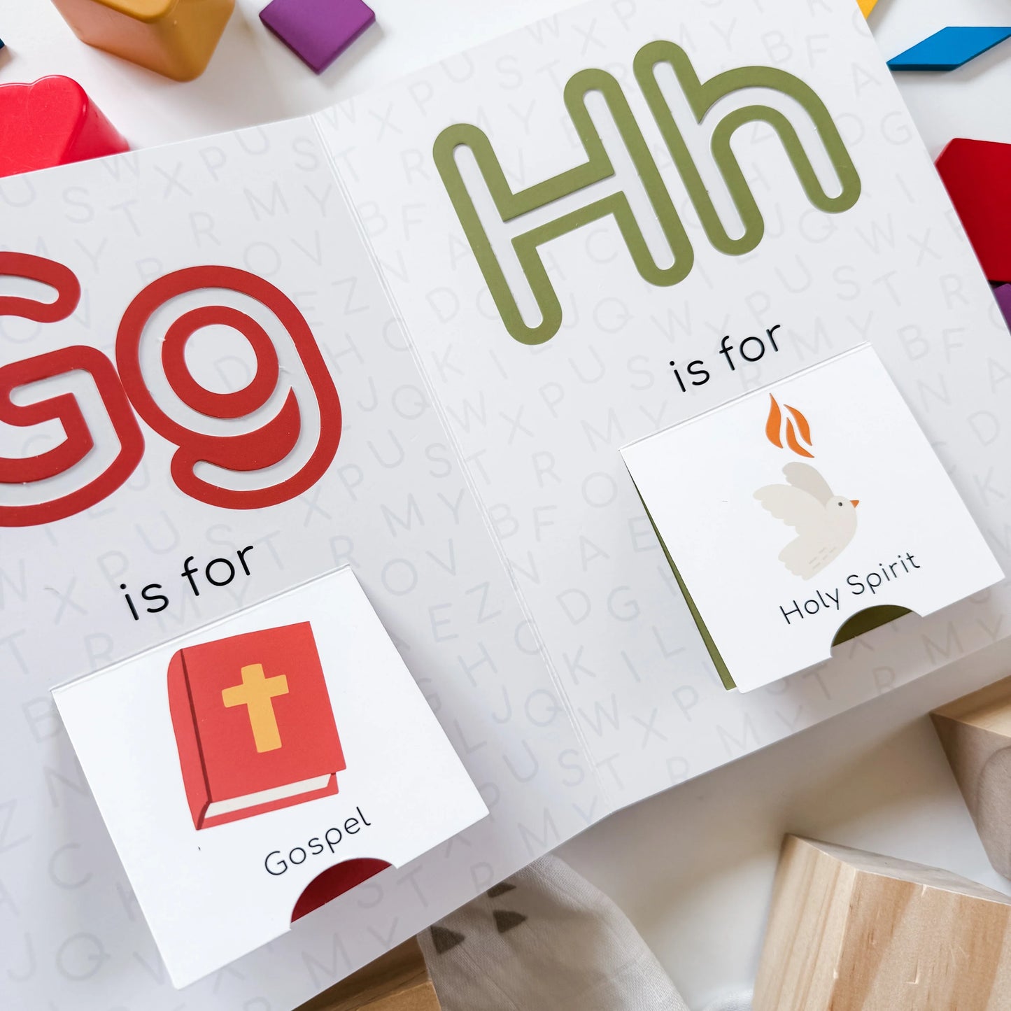 Pages showing Gg for Gospel with red Bible illustration and Hh for Holy Spirit with dove and flame in Catholic ABC board book