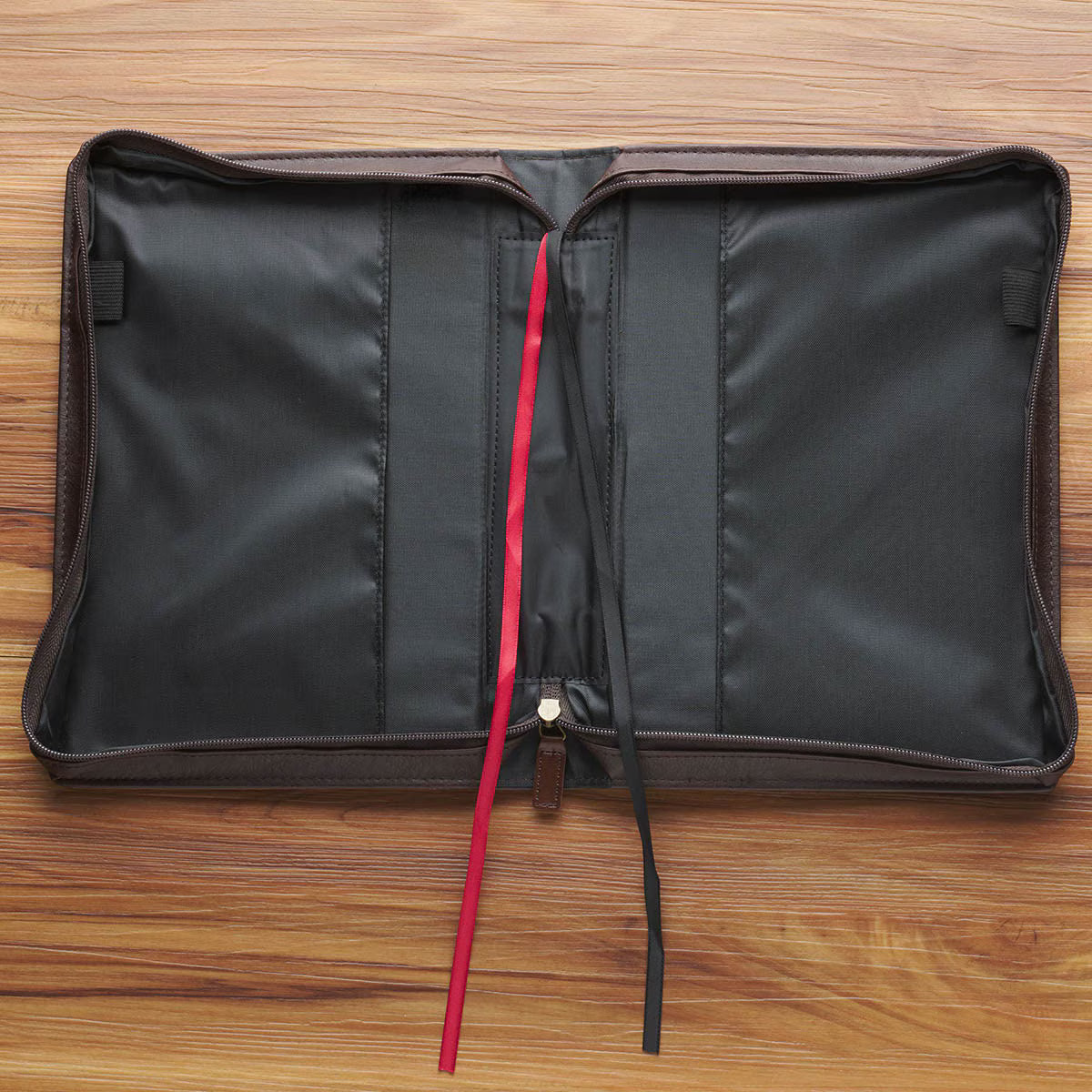 Open Crown of Thorns brown faux leather Bible cover with red and black ribbon bookmarks on wooden surface