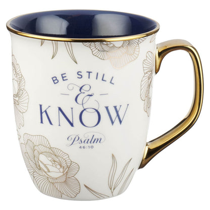 Ceramic mug with blue interior, gold handle, floral accents, and Psalm 46:10 "Be Still and Know" text design
