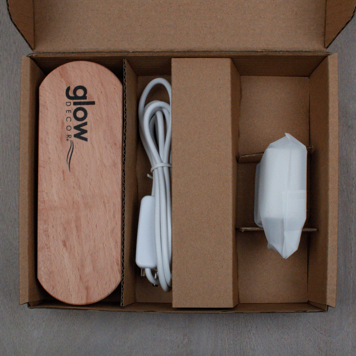 Unboxed Saint Joseph LED Nightlight components including wooden base, USB cord with switch, and white light module in cardboard packaging