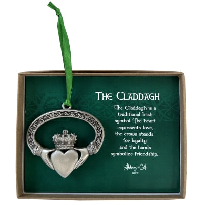Silver Claddagh Christmas ornament with heart, crown, and hands design on green card explaining its Irish symbolism