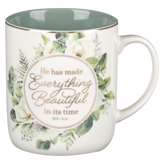 Ceramic coffee mug with green wreath design and Ecclesiastes 3:11 scripture in gold script on white background