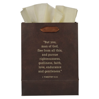 Brown medium gift bag with leather handle and 1 Timothy 6:11 scripture quote in cream text, filled with beige tissue paper