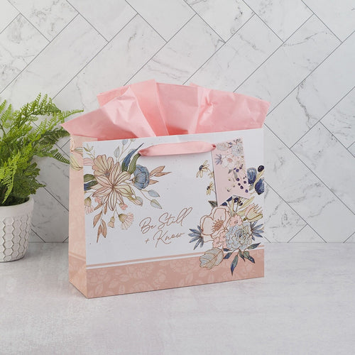 Large landscape gift bag with peach blossom floral design, "Be Still and Know" scripture, and pink tissue paper inside