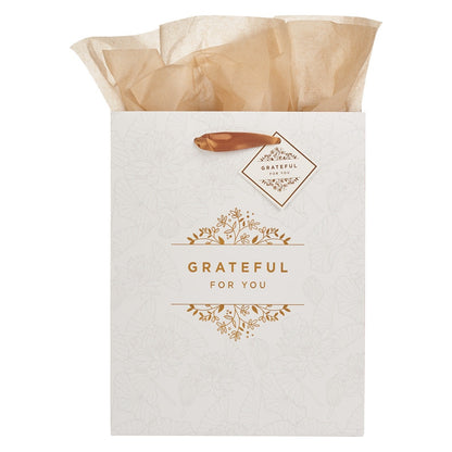 Medium white gift bag with gold "Grateful For You" text, floral design, satin handles, and beige tissue paper inside