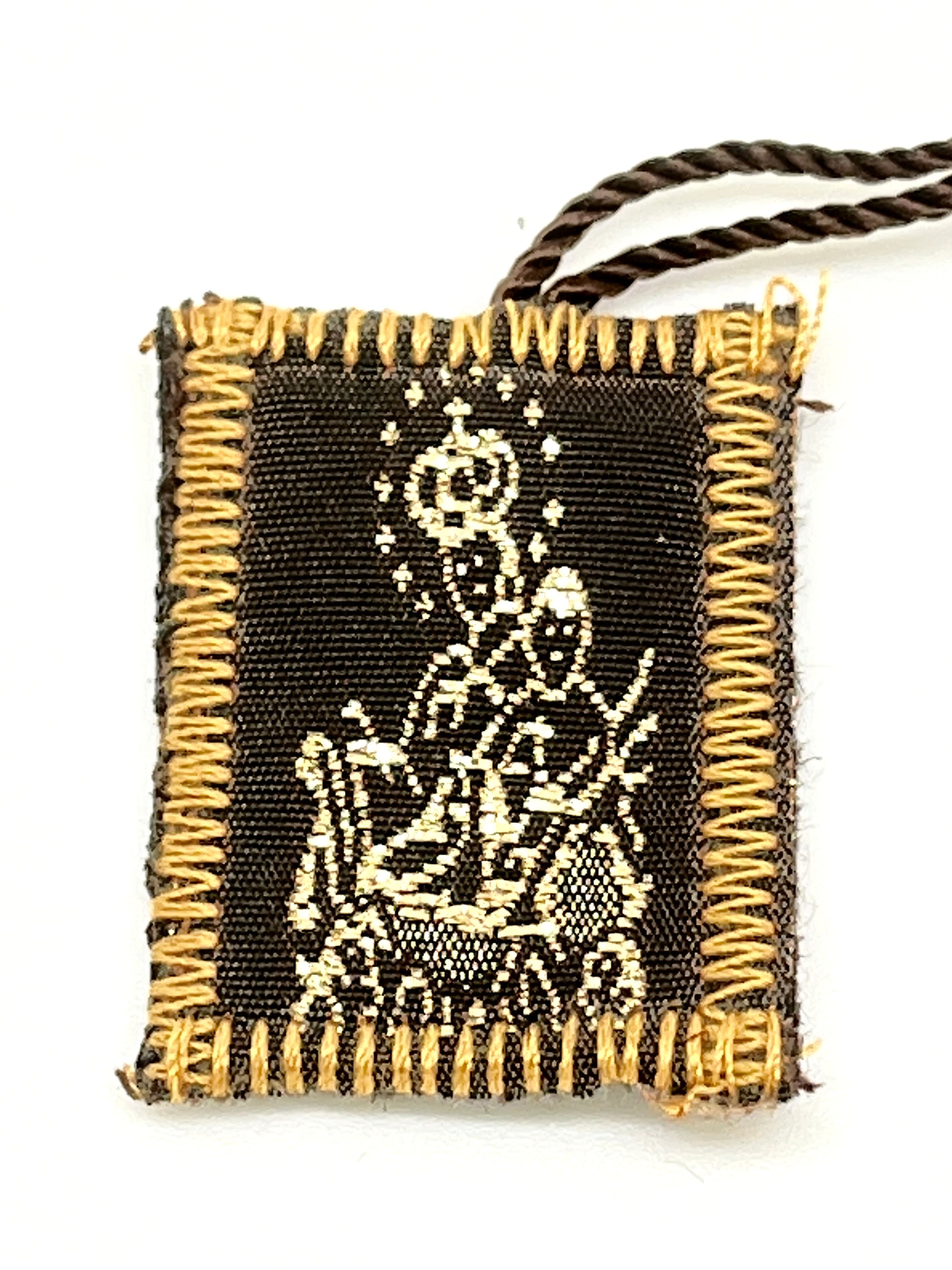 Brown scapular with wool embroidery depicting Our Lady of Mount Carmel, edged with tan stitching and attached cords