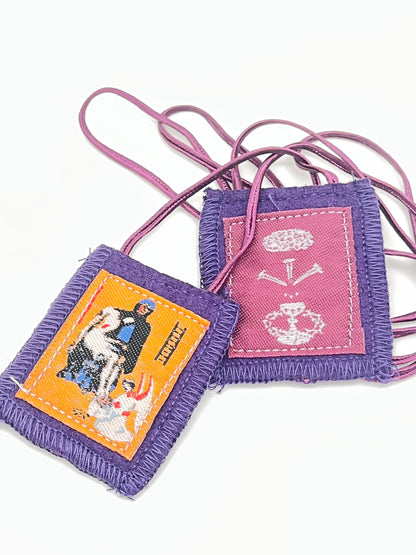 Purple scapular with embroidered images of Mary and Jesus, edged in purple fabric with purple cords for wearing.