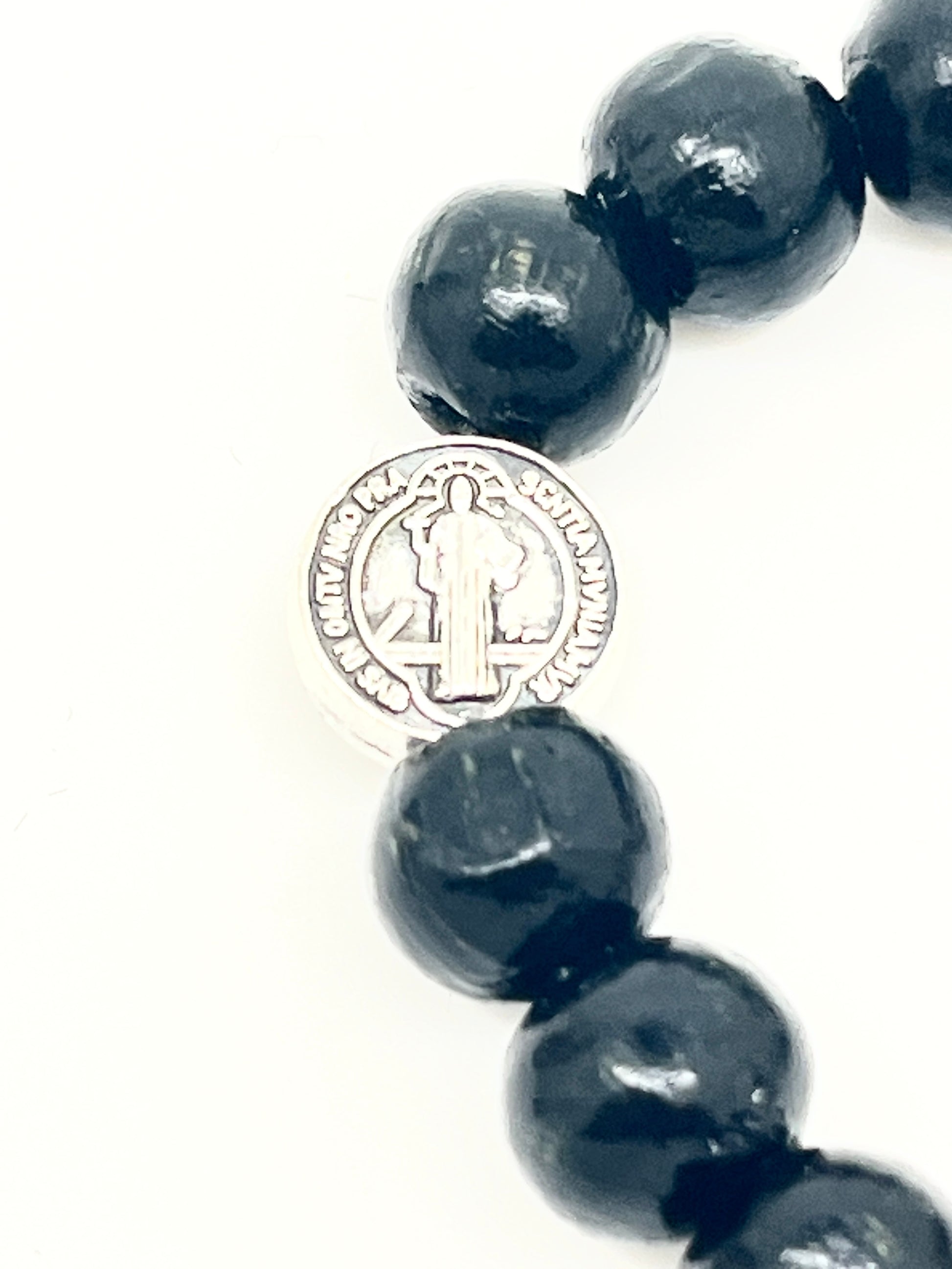 Black wood bead bracelet featuring a silver St. Benedict Medal with detailed engraving on adjustable slip knot design
