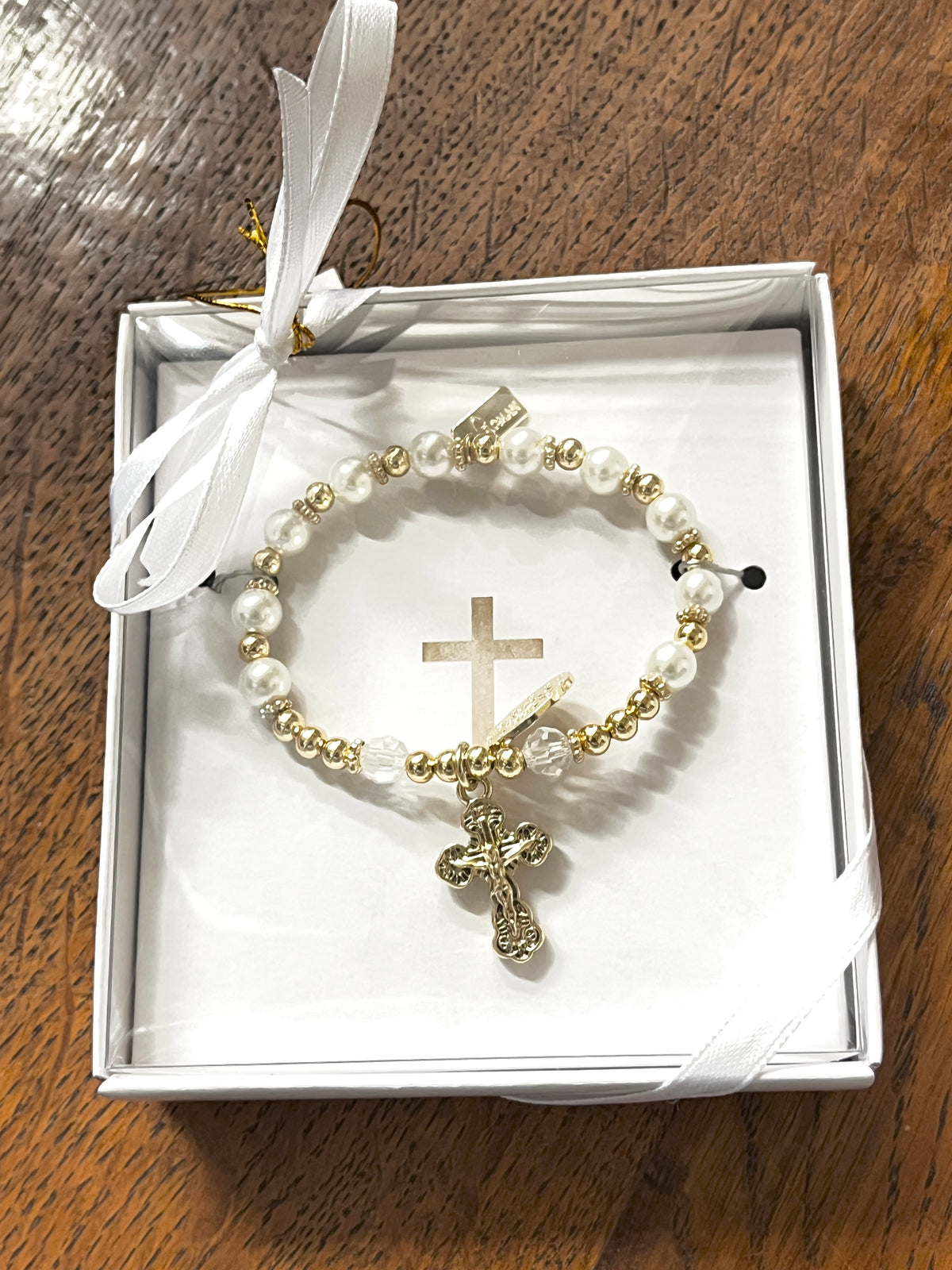 Silver and white glass pearl rosary bracelet with gold-tone Miraculo cross, presented in white gift box with ribbon.