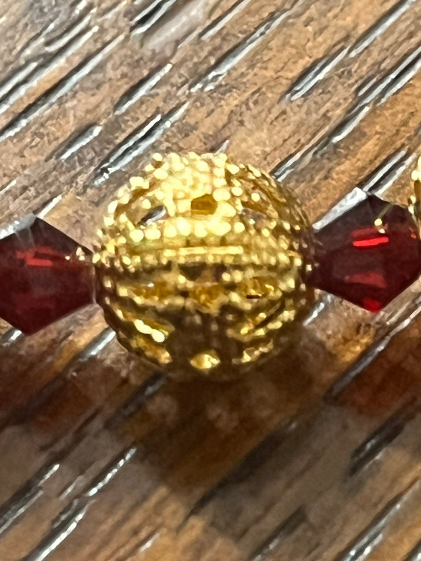 Close-up of gold filigree bead between deep red glass beads on Immaculate Heart of Mary Rosary with gold accents