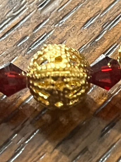 Close-up of gold filigree bead between deep red glass beads on Immaculate Heart of Mary Rosary with gold accents