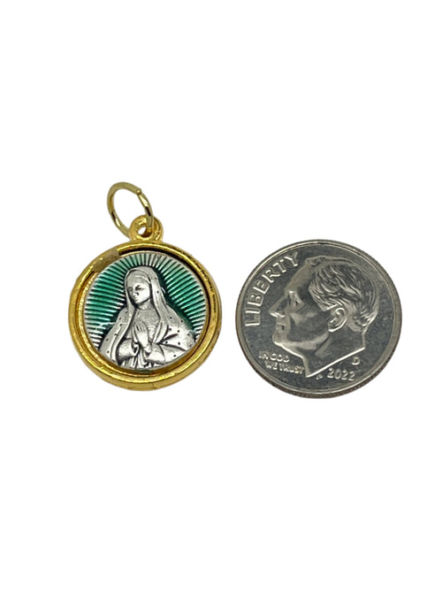 Small round Our Lady of Guadalupe medal with gold trim and green enamel background next to a U.S. dime for scale