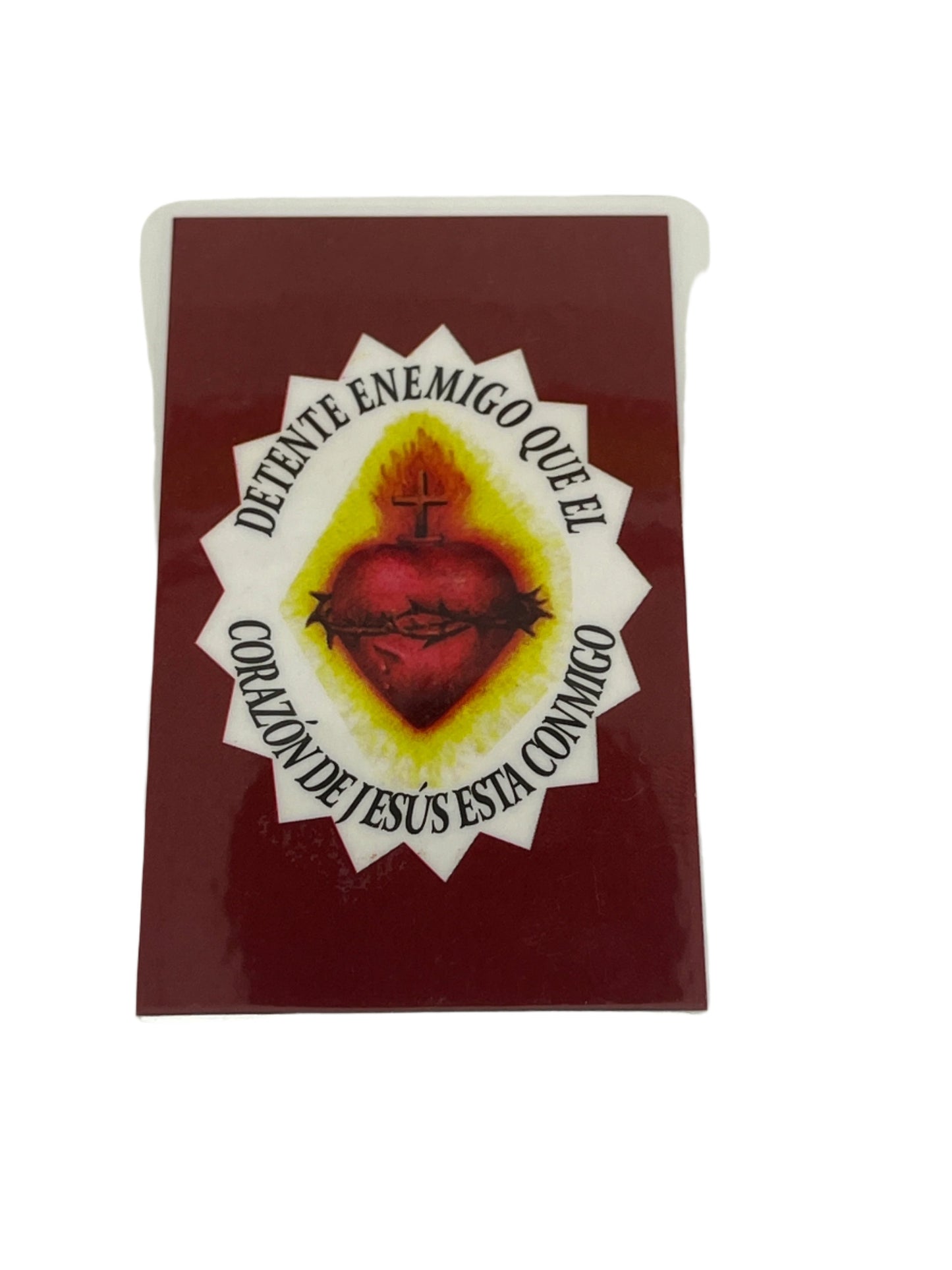 Laminated holy card with Sacred Heart of Jesus image and "Detente Enemigo" prayer in Spanish text around heart.