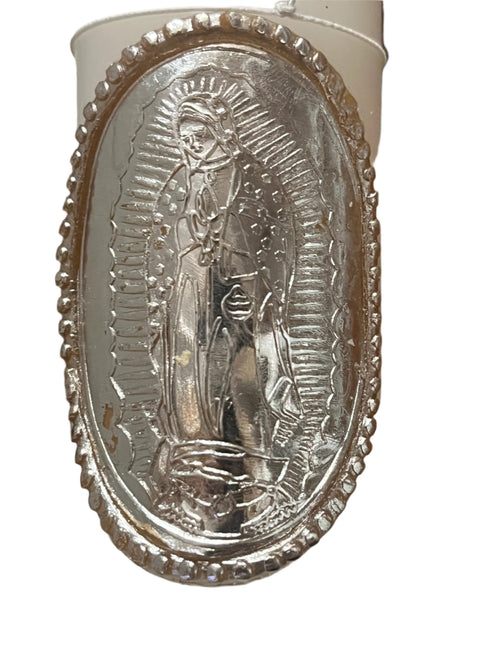Close-up of silver Our Lady of Guadalupe decoration on white baptism candle with detailed border design.