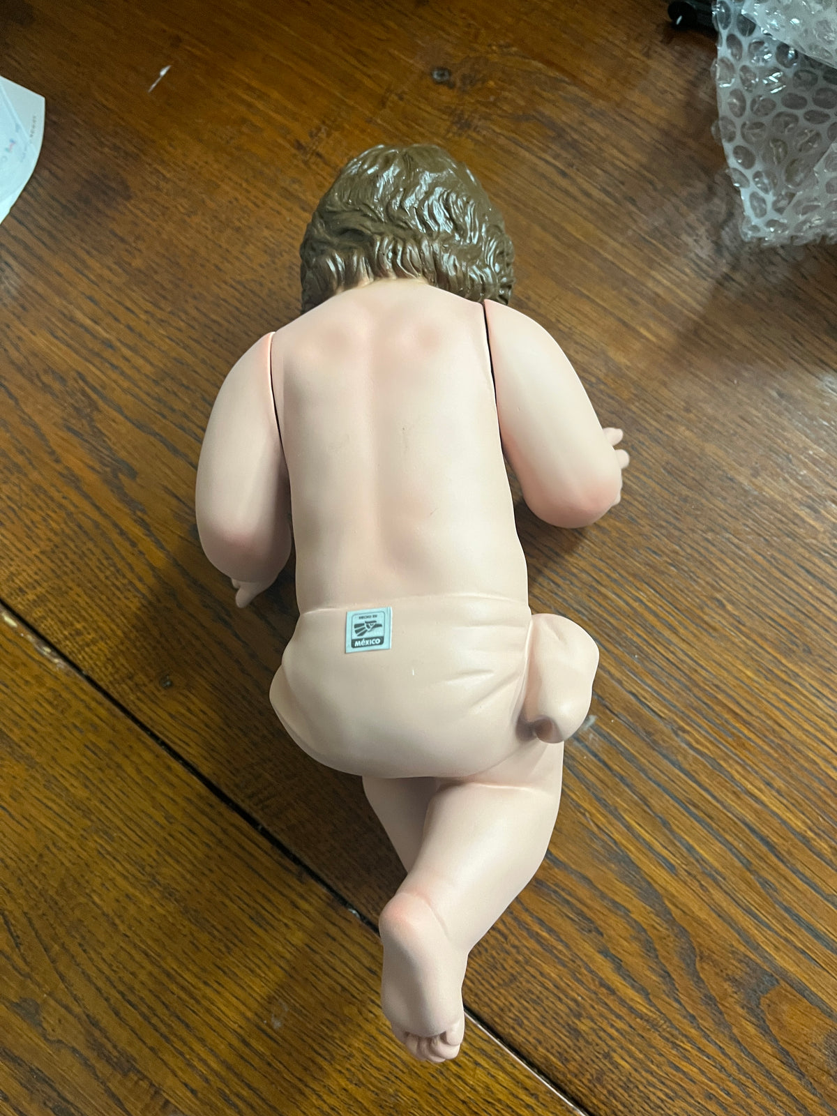 Hand-painted 8-inch Baby Jesus figurine made from resin mix with movable arms and realistic glass eyes, shown from back.