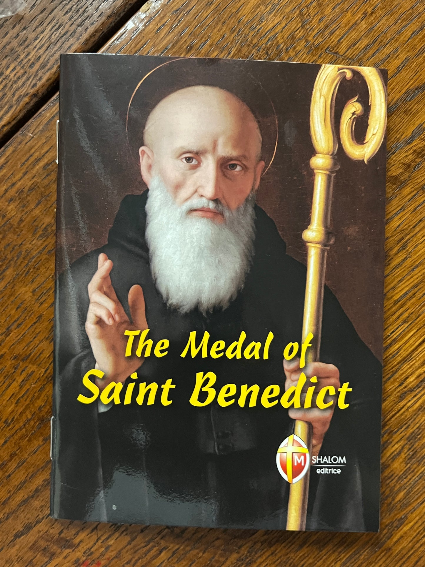 Book cover showing Saint Benedict with staff, white beard, black robe, and title The Medal of Saint Benedict in yellow text