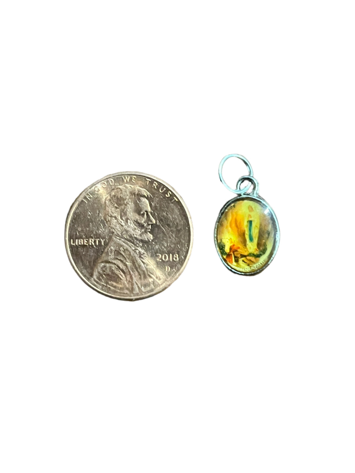 Small oval Our Lady of Lourdes medal charm with colorful image, size shown next to 2018 penny coin for scale