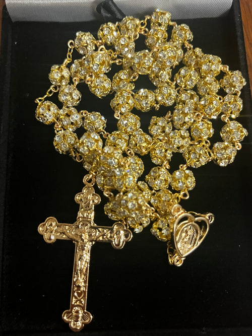 Gold wrapped rosary with sparkling crystal beads and detailed crucifix, presented in black velvet box.