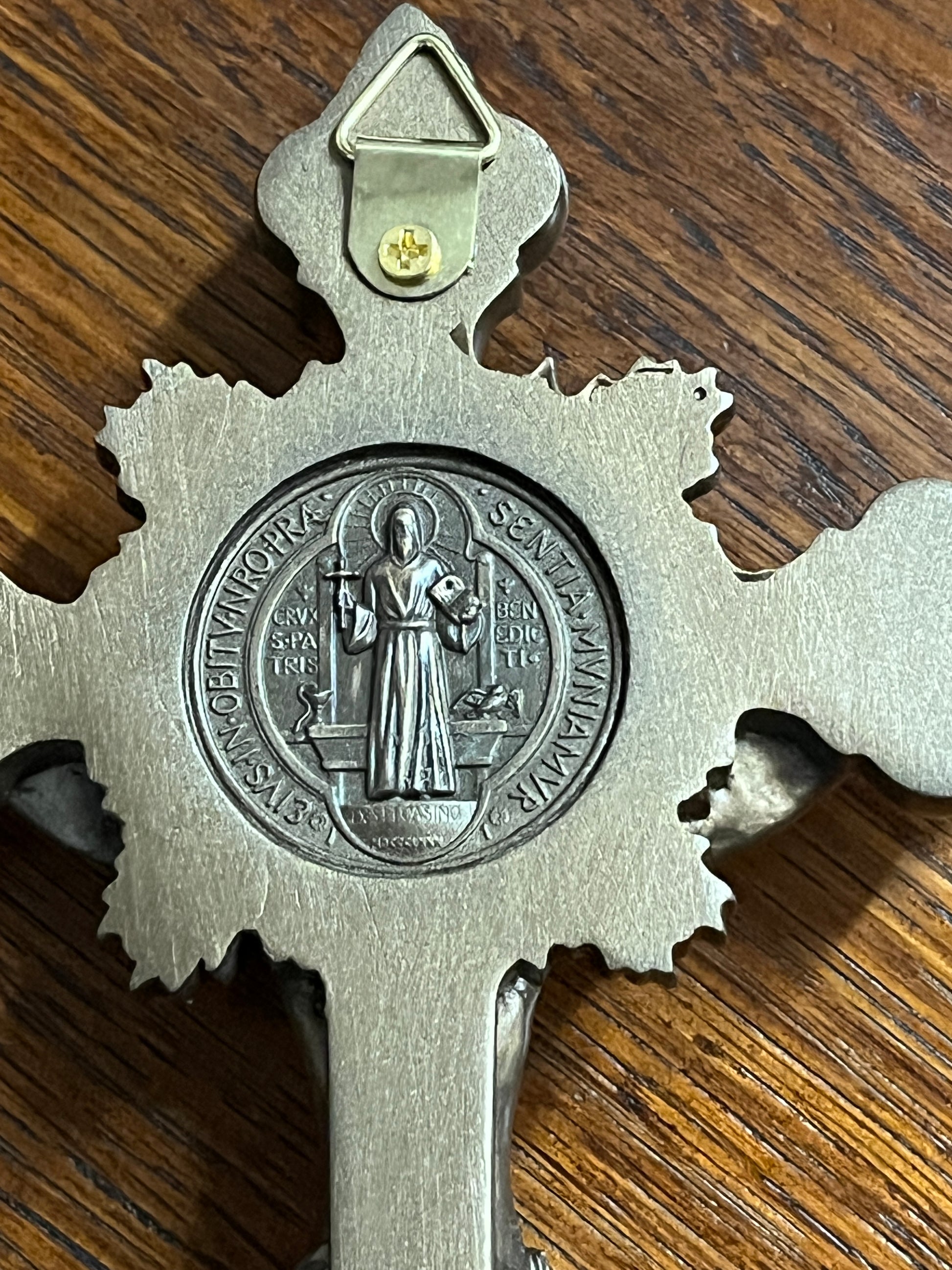 Close-up of St. Benedict medal on bronze-toned standing crucifix with detailed engraving and wall hanging hook