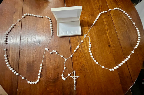 White 12MM faux pearl wedding lasso rosary with silver-tone crucifix and Madonna and child centerpiece displayed on wood table