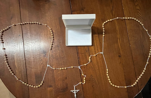 10mm gold faux pearl lasso rosary with delicate chain and crucifix, displayed on wooden surface with white jewelry box