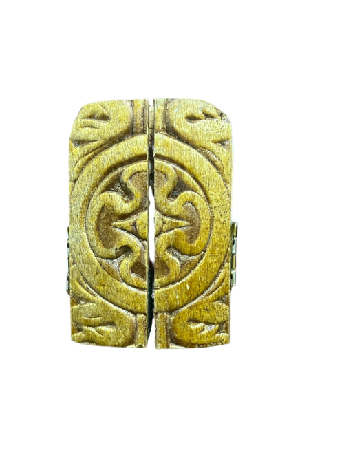 Closed wooden triptych with carved ornate circular pattern and hinges on white background