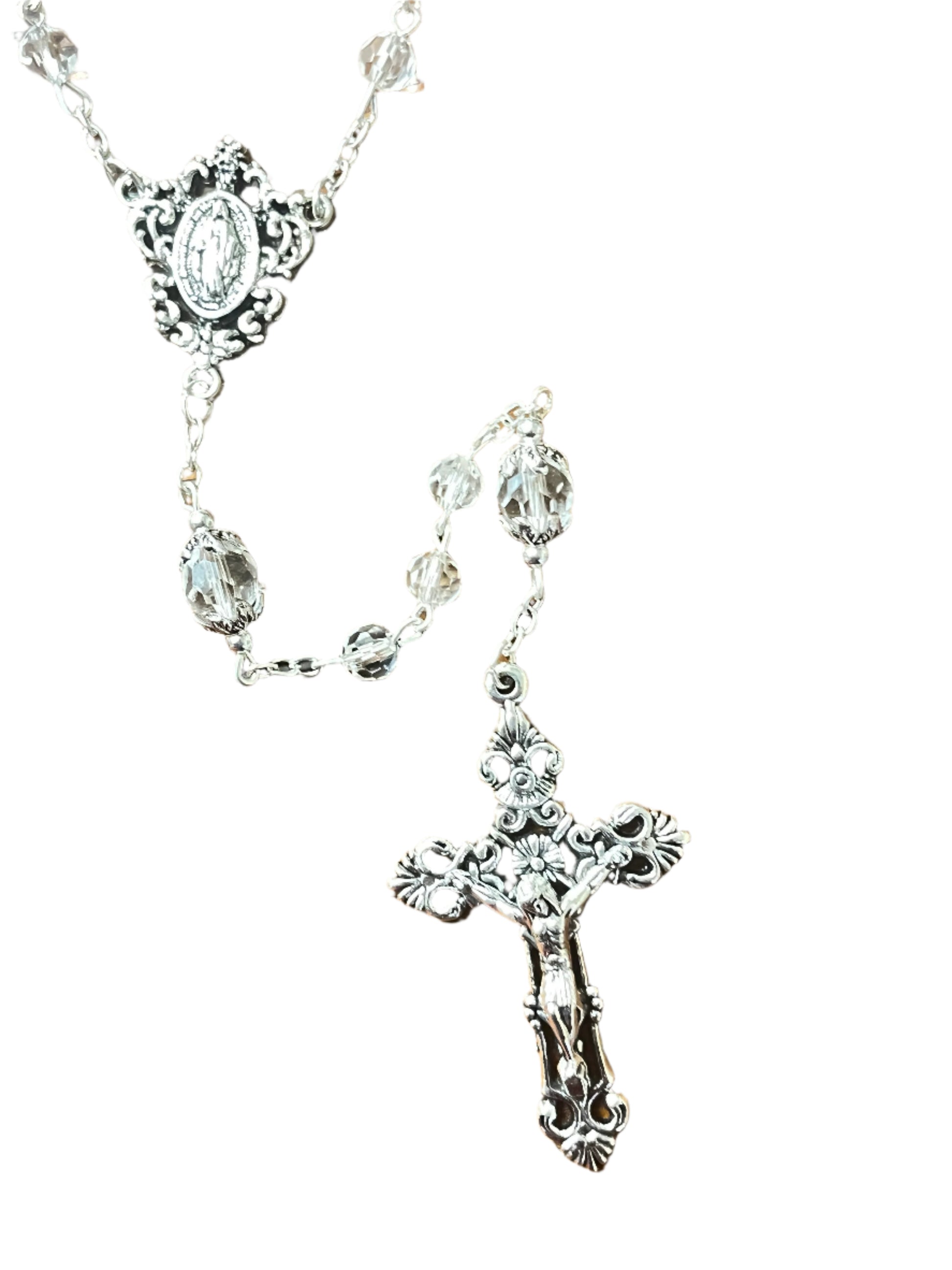 Close-up of clear crystal rosary with silver Our Lady of Grace centerpiece and ornate crucifix on white background