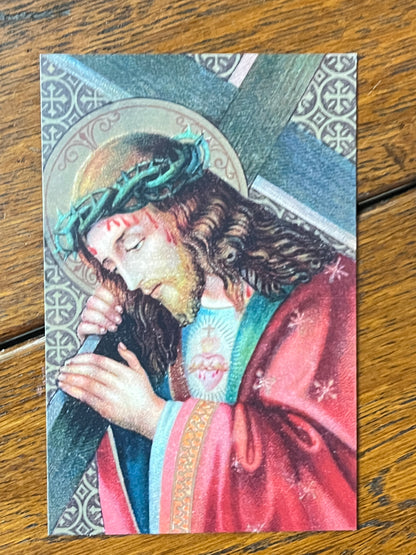 Holy card depicting Jesus carrying the cross wearing crown of thorns and red robe with sacred heart visible
