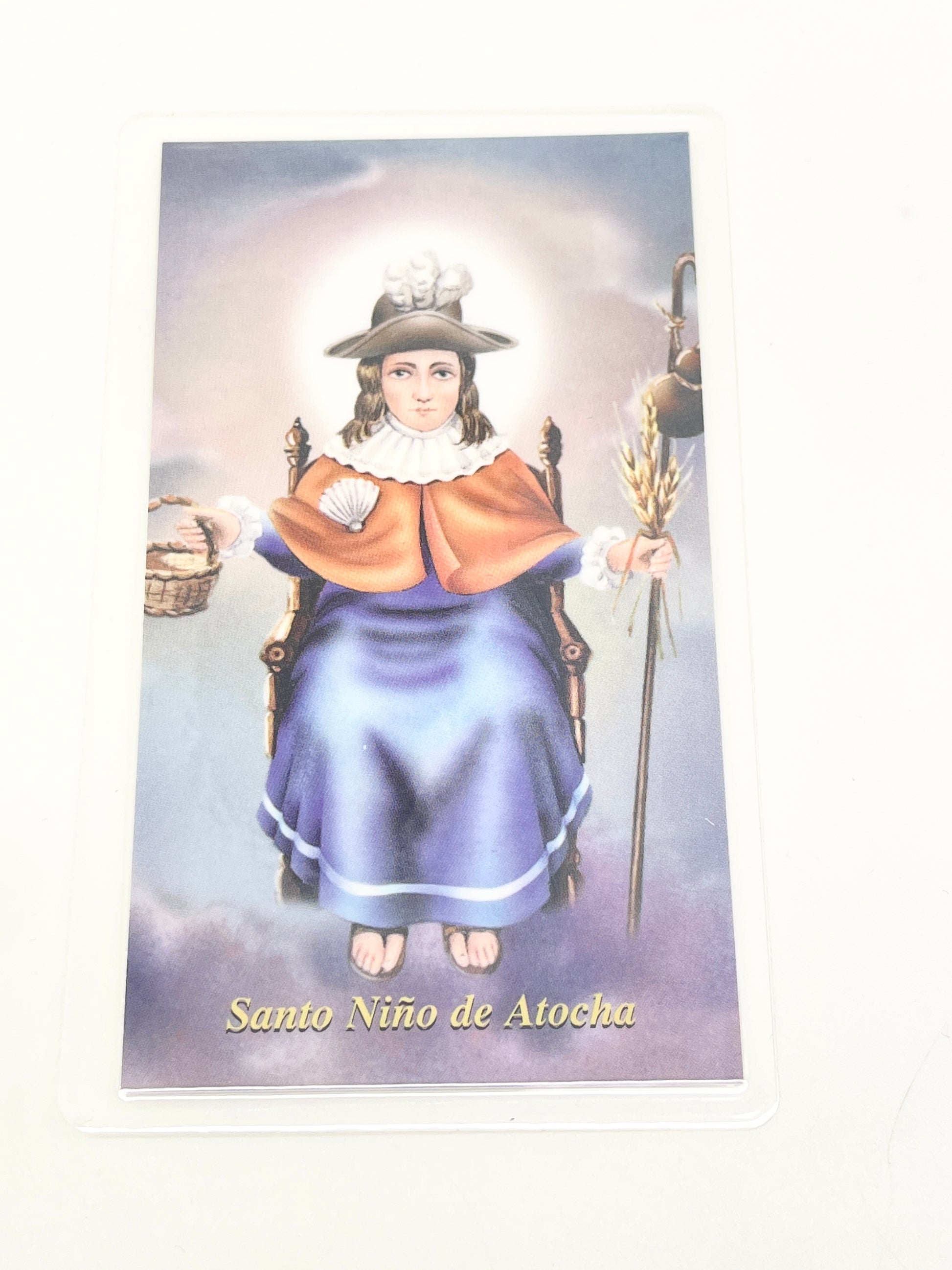 Laminated holy card of Santo Niño de Atocha seated with staff, basket, wheat and prayer on the back
