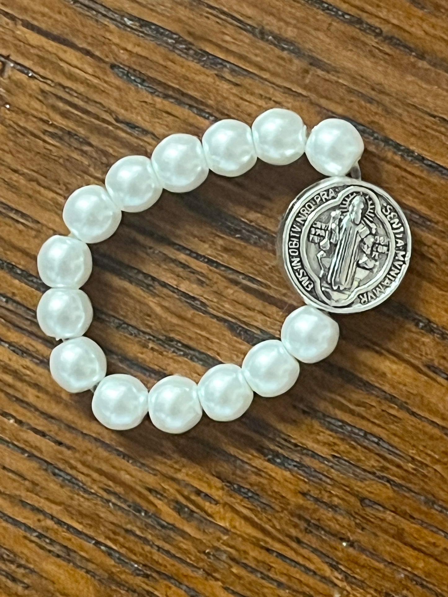White stretch ring with pearl-like beads and silver-toned Benedict medal featuring sacred religious engraving