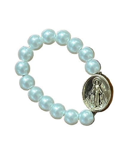 White bead stretch ring with gold Miraculous Medal charm, symbolizing faith and devotion in elegant design