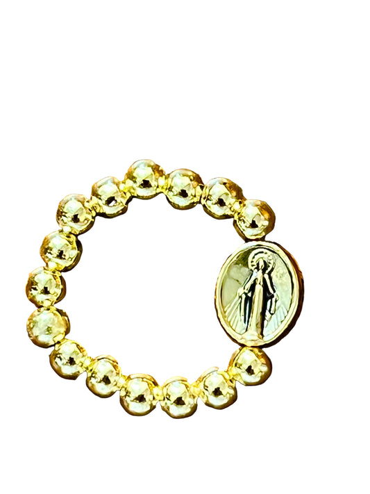 Gold-toned stretch ring with round beads and oval Miraculous Medal featuring Virgin Mary engraving on white background