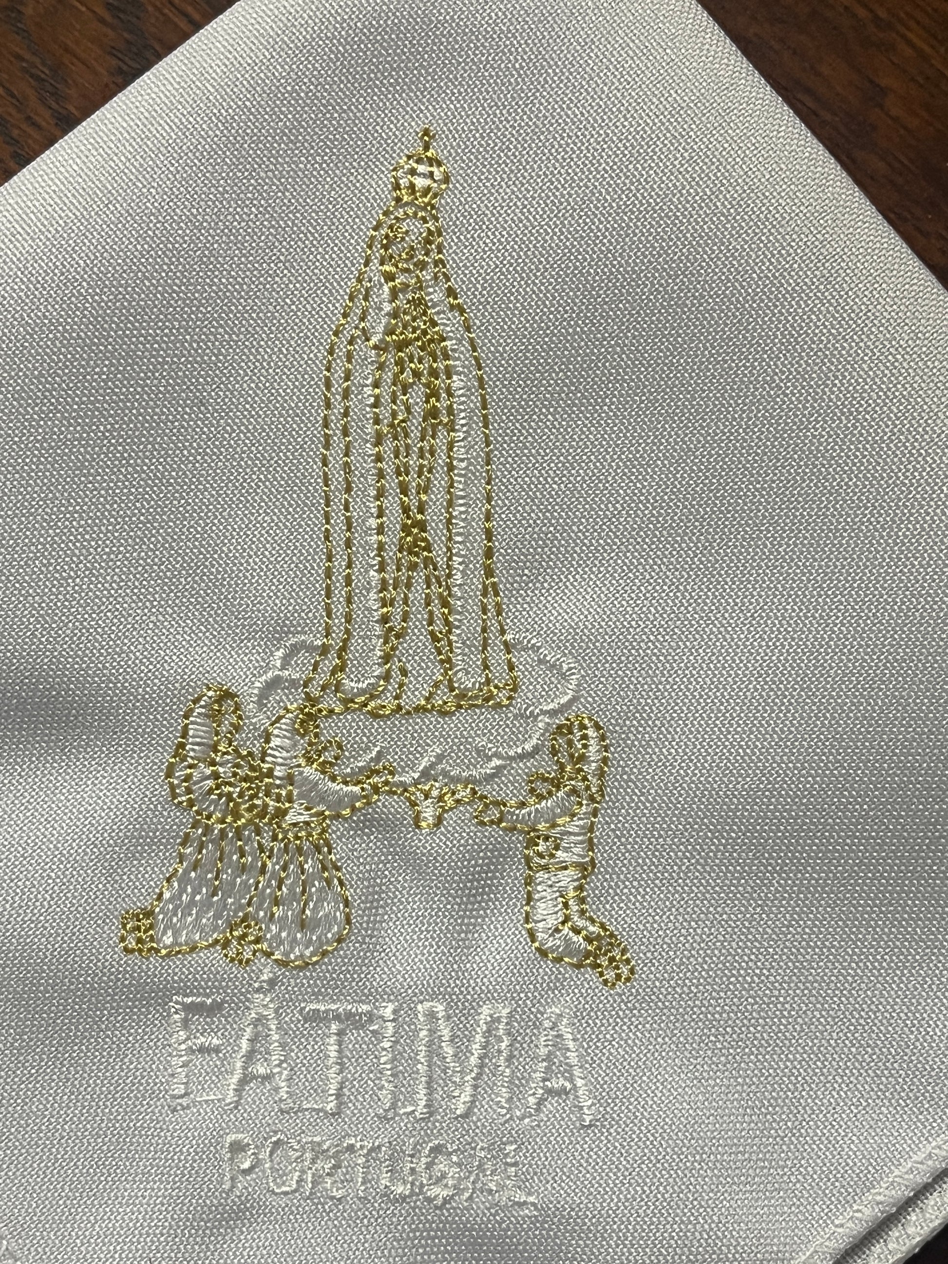 Embroidered white handkerchief with gold and white depiction of Our Lady of Fatima and kneeling angels with Fatima Portugal text