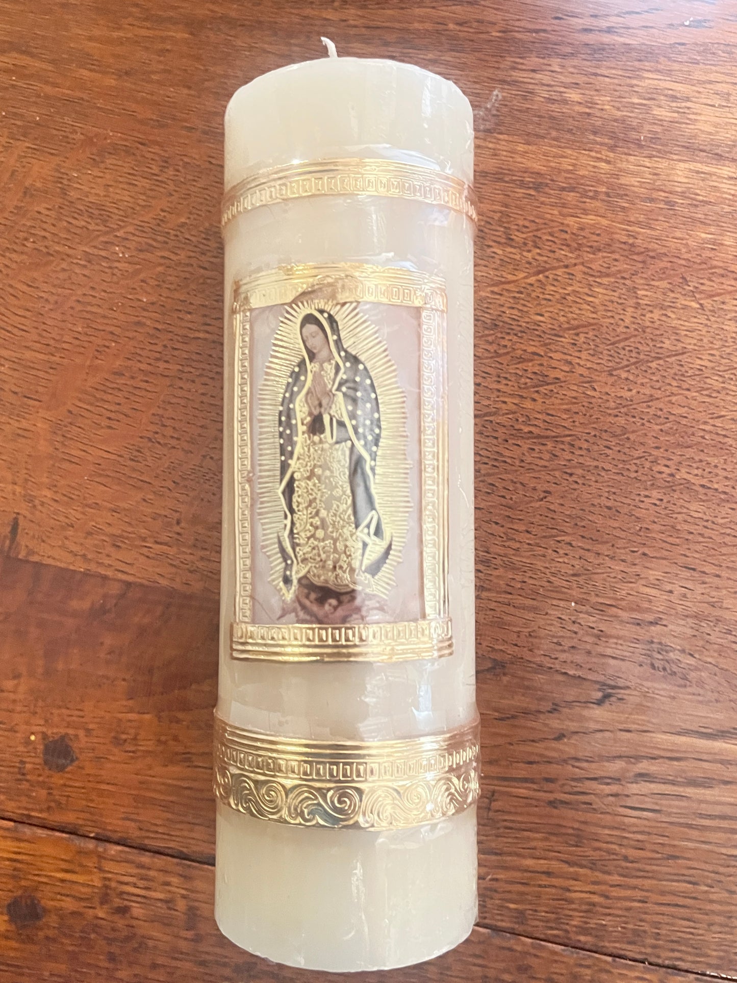 Our Lady of Guadalupe beeswax candle 7 3/4" with gold decorative borders on wooden surface