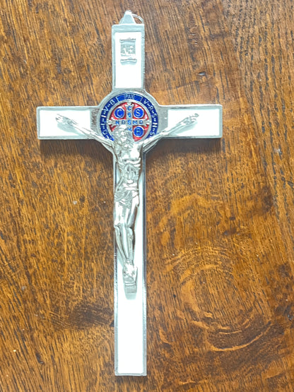 White enamel St. Benedict crucifix with multicolor medal, silver Jesus figure, displayed on wooden surface