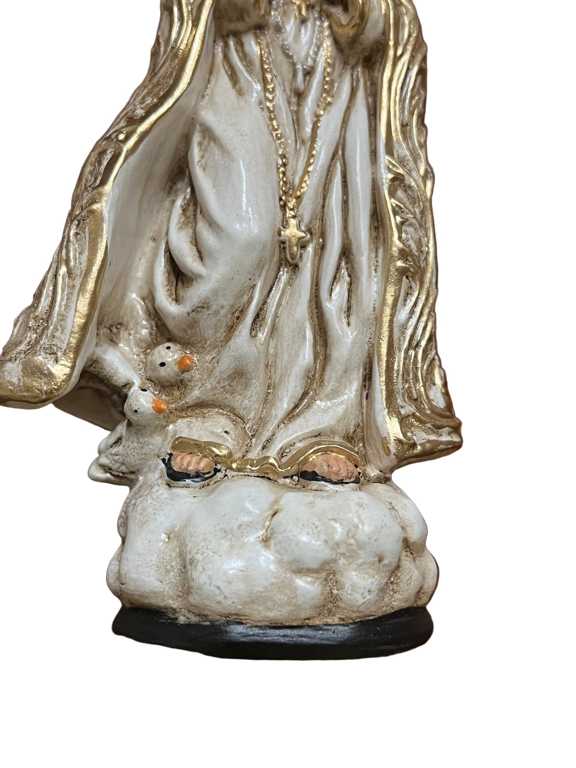 Close-up of Our Lady of Fatima statue base with golden robe, rosary, and two white doves on cloud-shaped pedestal